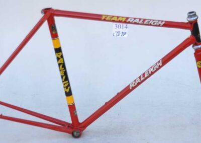 A red bicycle frame with yellow lettering on it.