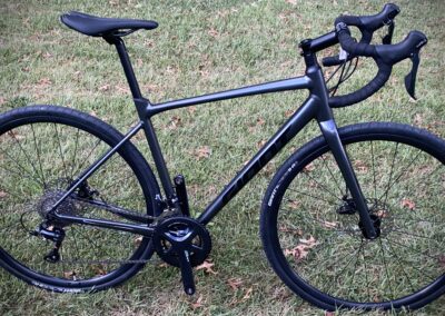 A black bike is parked in the grass.